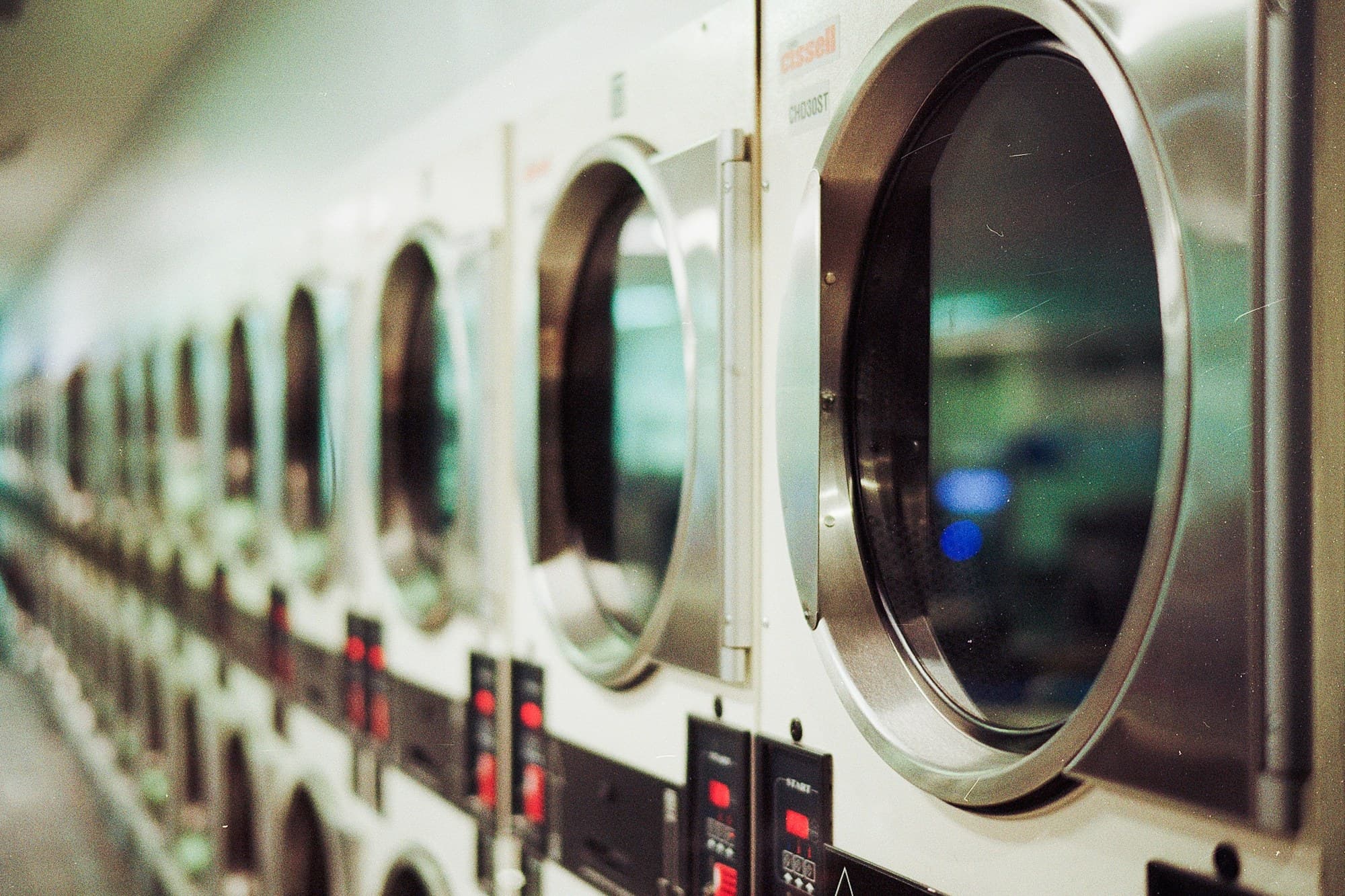 A long row of commercial dryers with their doors open